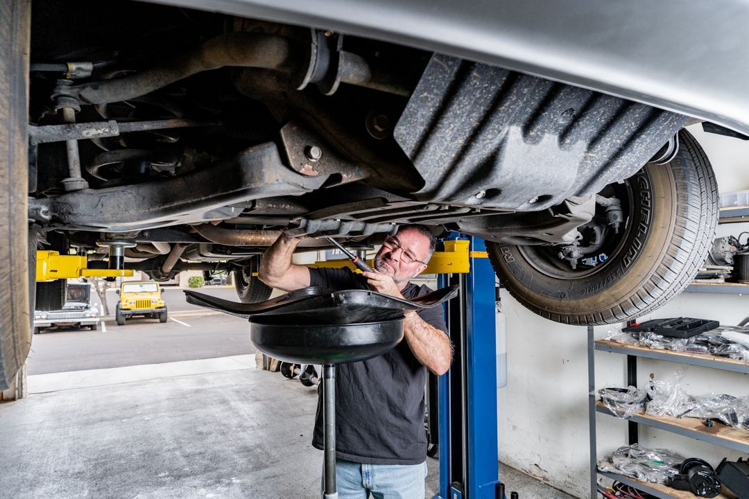 A man is working under a car on a lift in a garage.