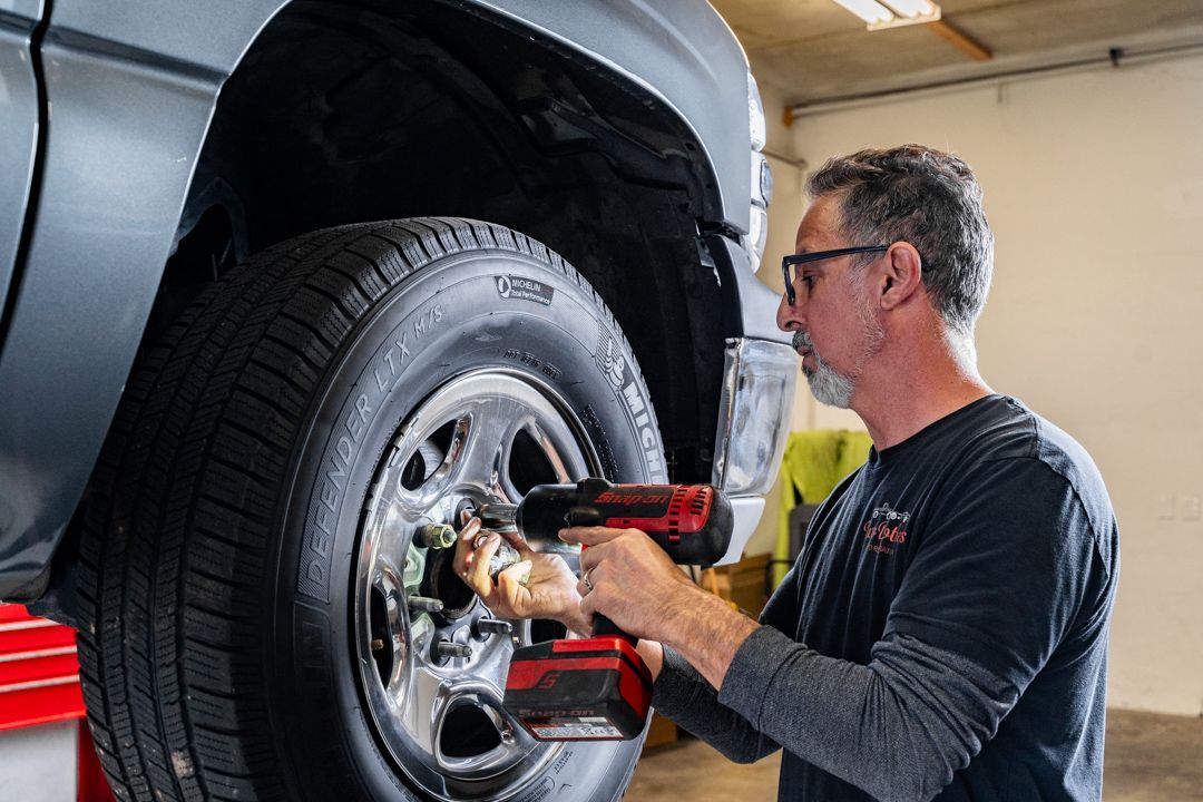 A man is working on a tire on a truck in a garage.