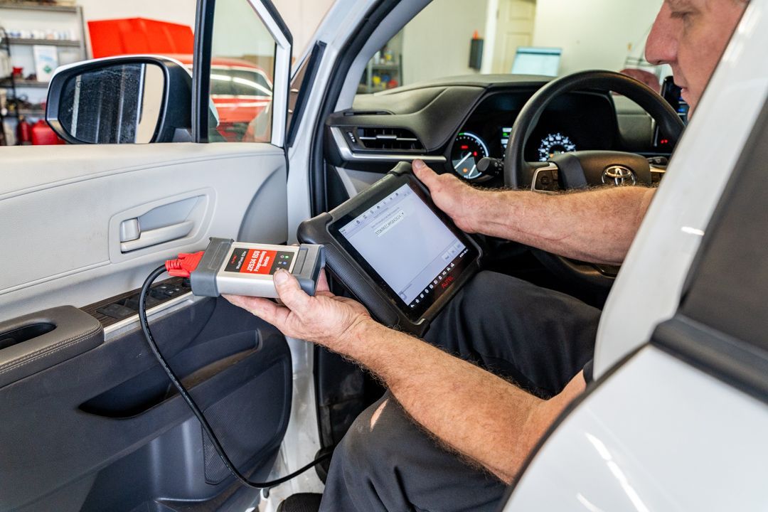 A man is sitting in a car holding a tablet.