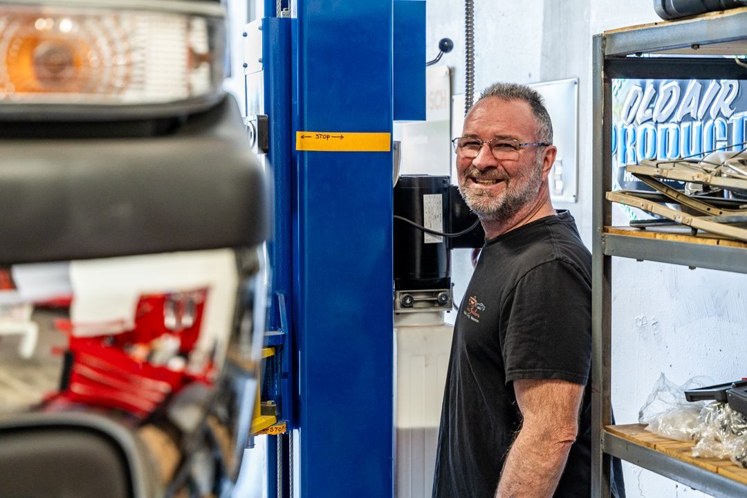A man is standing in front of a car lift in a garage.