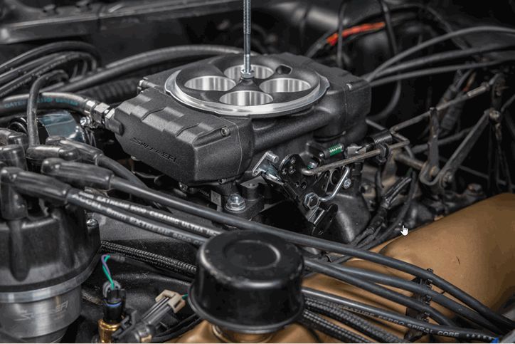 A close up of a car engine with a carburetor.