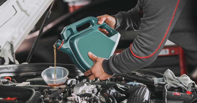 A man is pouring oil into a car engine.