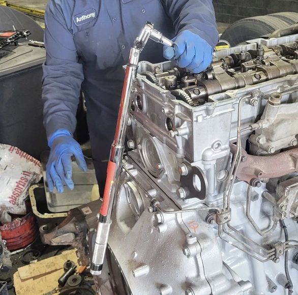 A man wearing blue gloves is working on a car engine