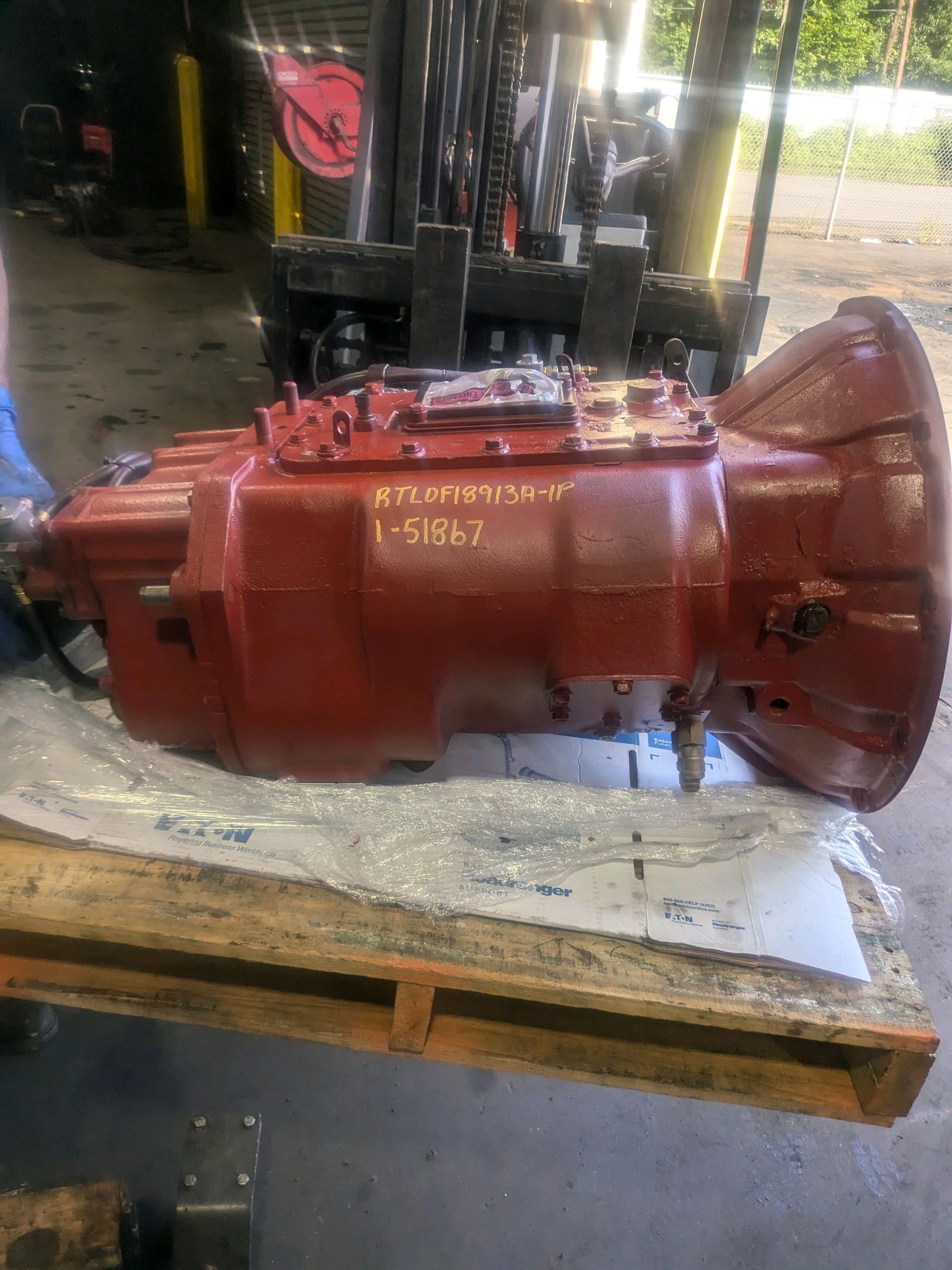 A red gearbox is sitting on top of a wooden pallet.
