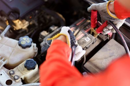 A person is charging a car battery with a jump starter.