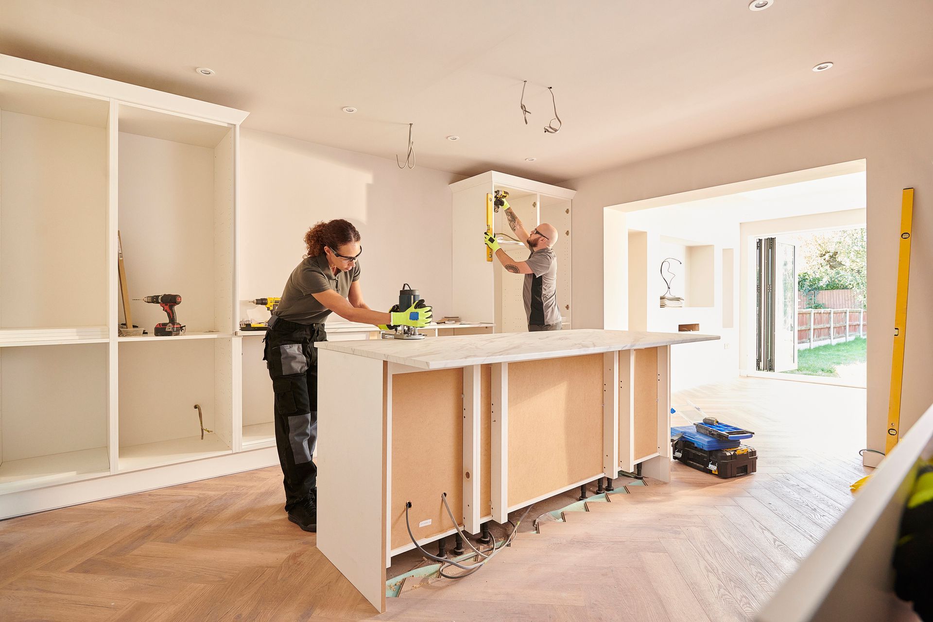 Two workers are in the process of remodeling a kitchen.
