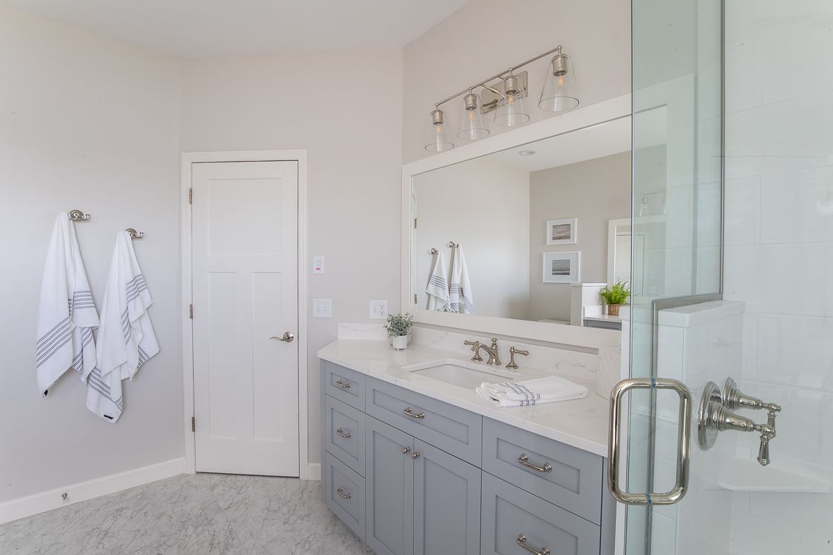 A Bathroom with Two Sinks , a Large Mirror and A Walk in Shower.