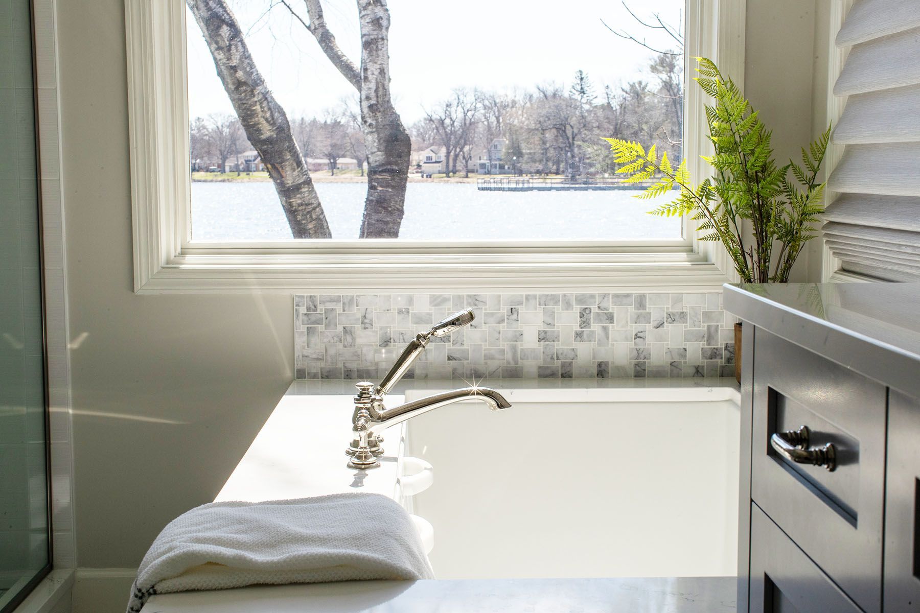 A Bathroom with A Tub and A Window Overlooking a Lake.