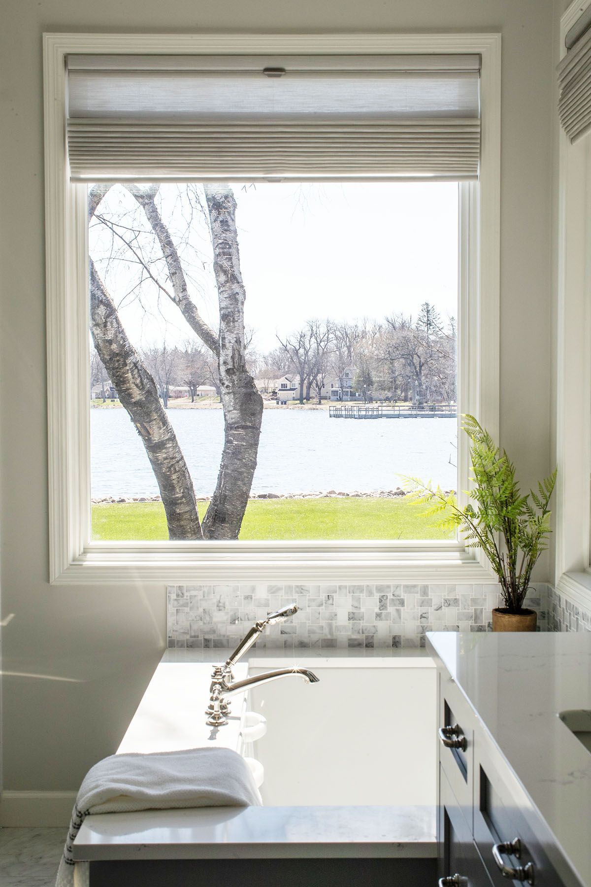 A Bathroom with A Tub and A Window Overlooking a Lake.