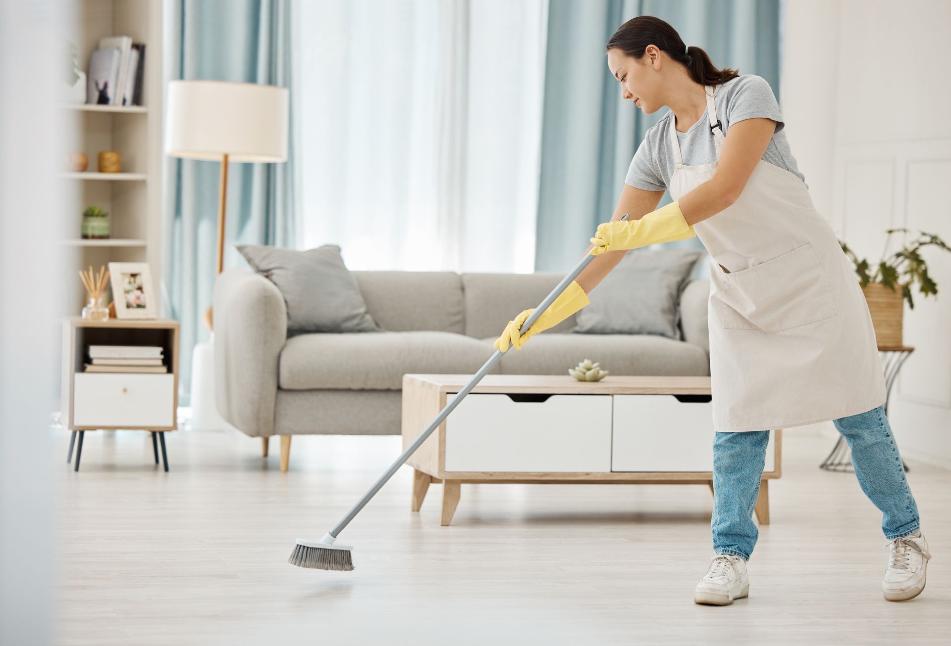 a woman is cleaning the floor in a living room with a mop .