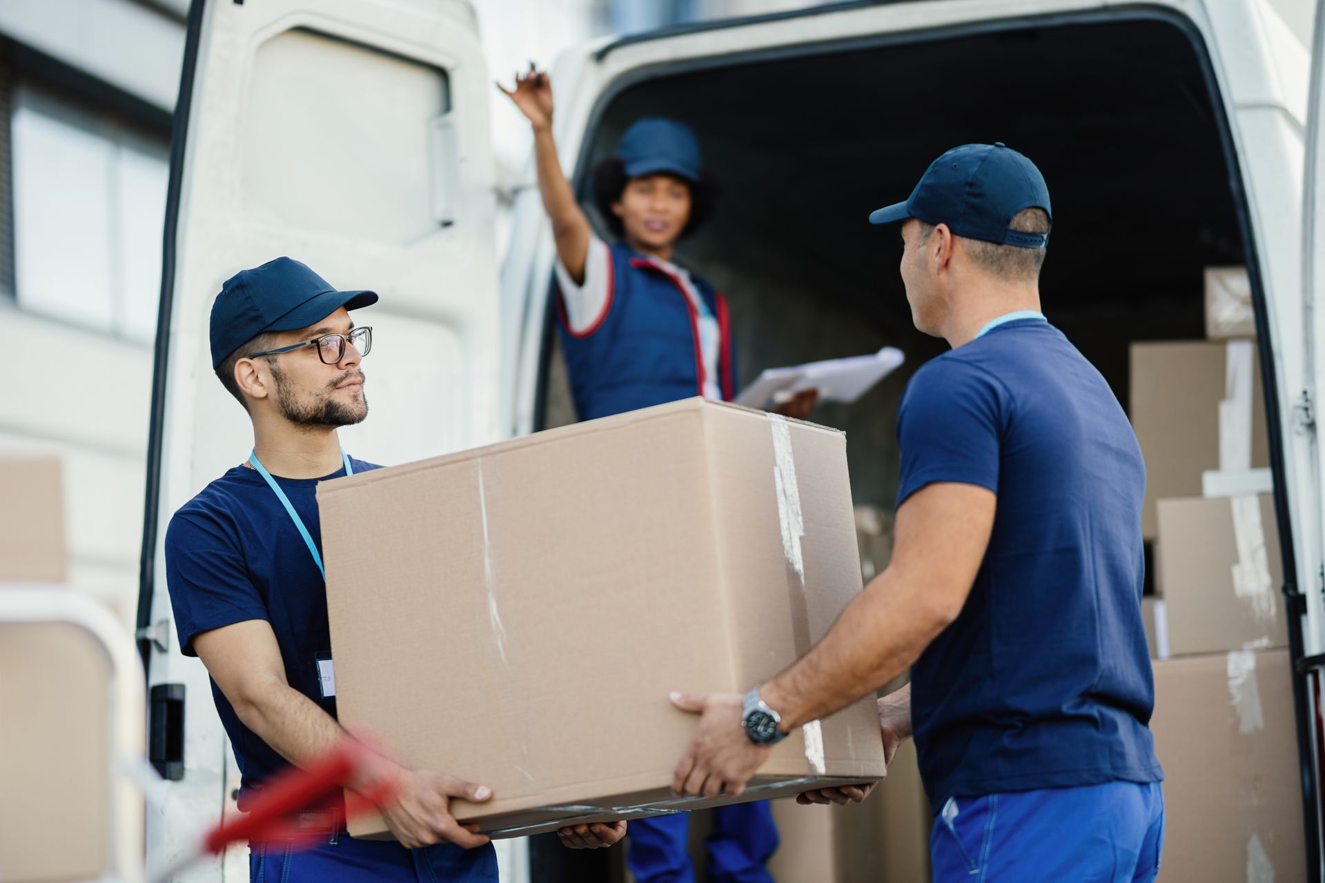 a group of movers are loading boxes into a van .