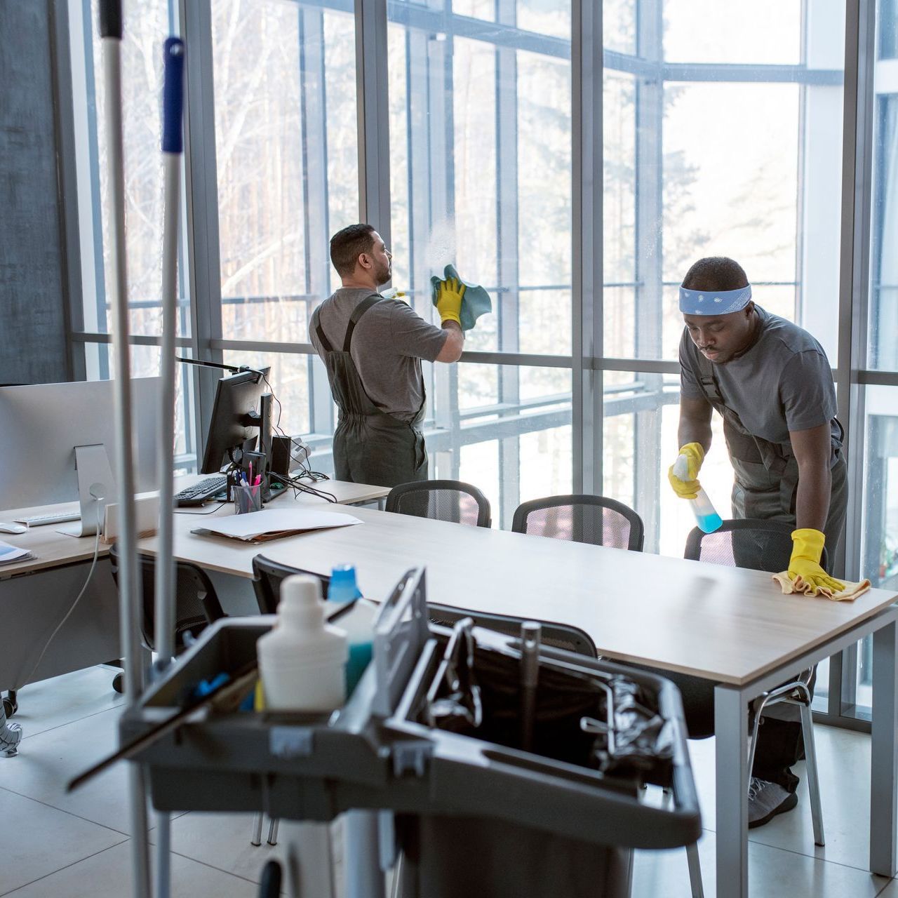 Two men are cleaning the windows of an office building.