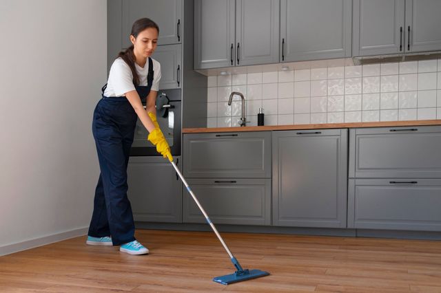 a woman is cleaning the floor in a kitchen with a mop .