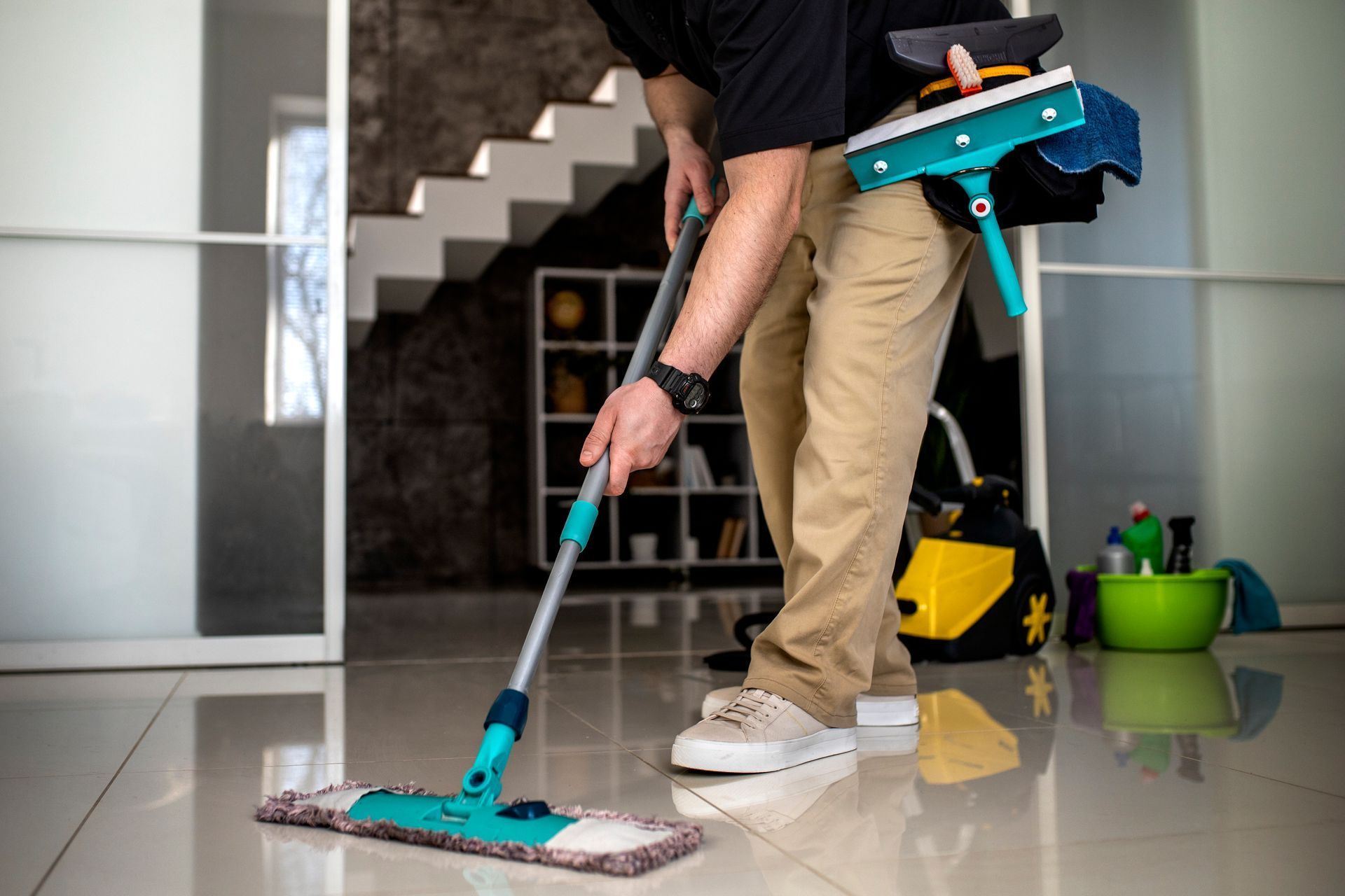 Person mopping a shiny tiled floor indoors.