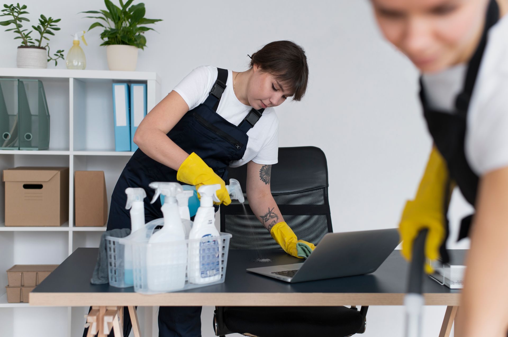 a woman is cleaning a desk in an office with a laptop .