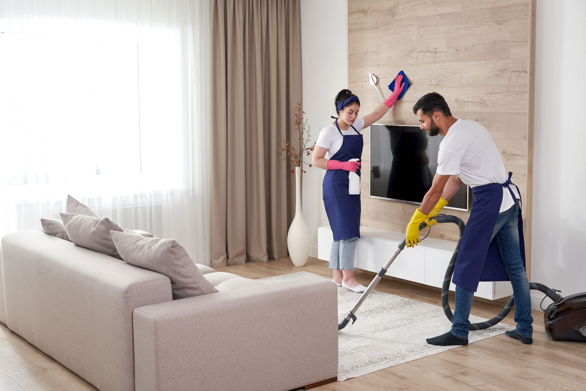 a man and a woman are cleaning a living room .