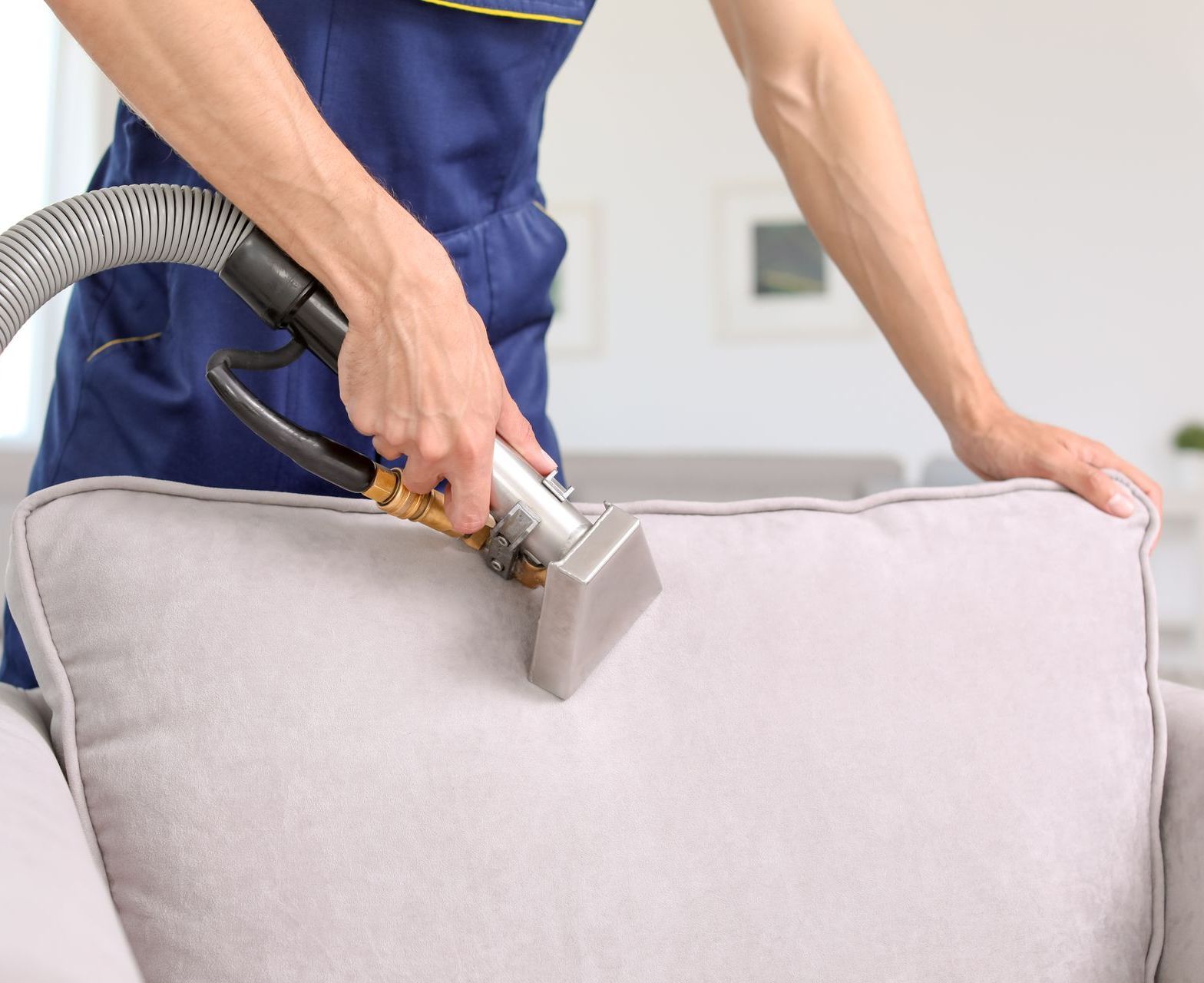 a person is cleaning a couch with a vacuum cleaner .