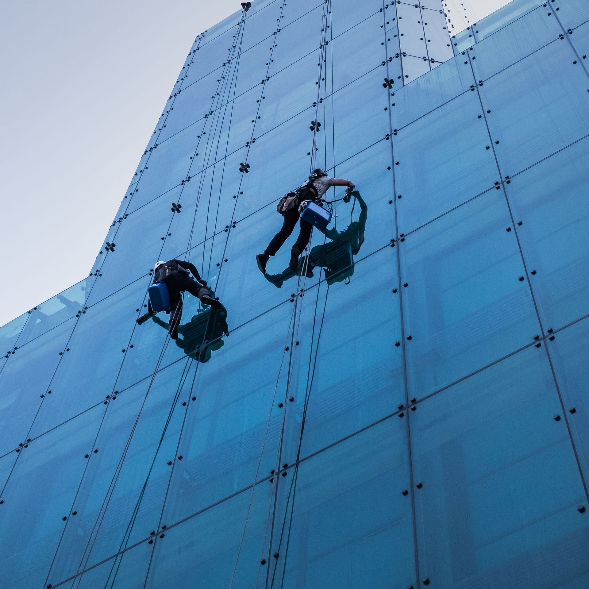 2 men cleaning glass window building