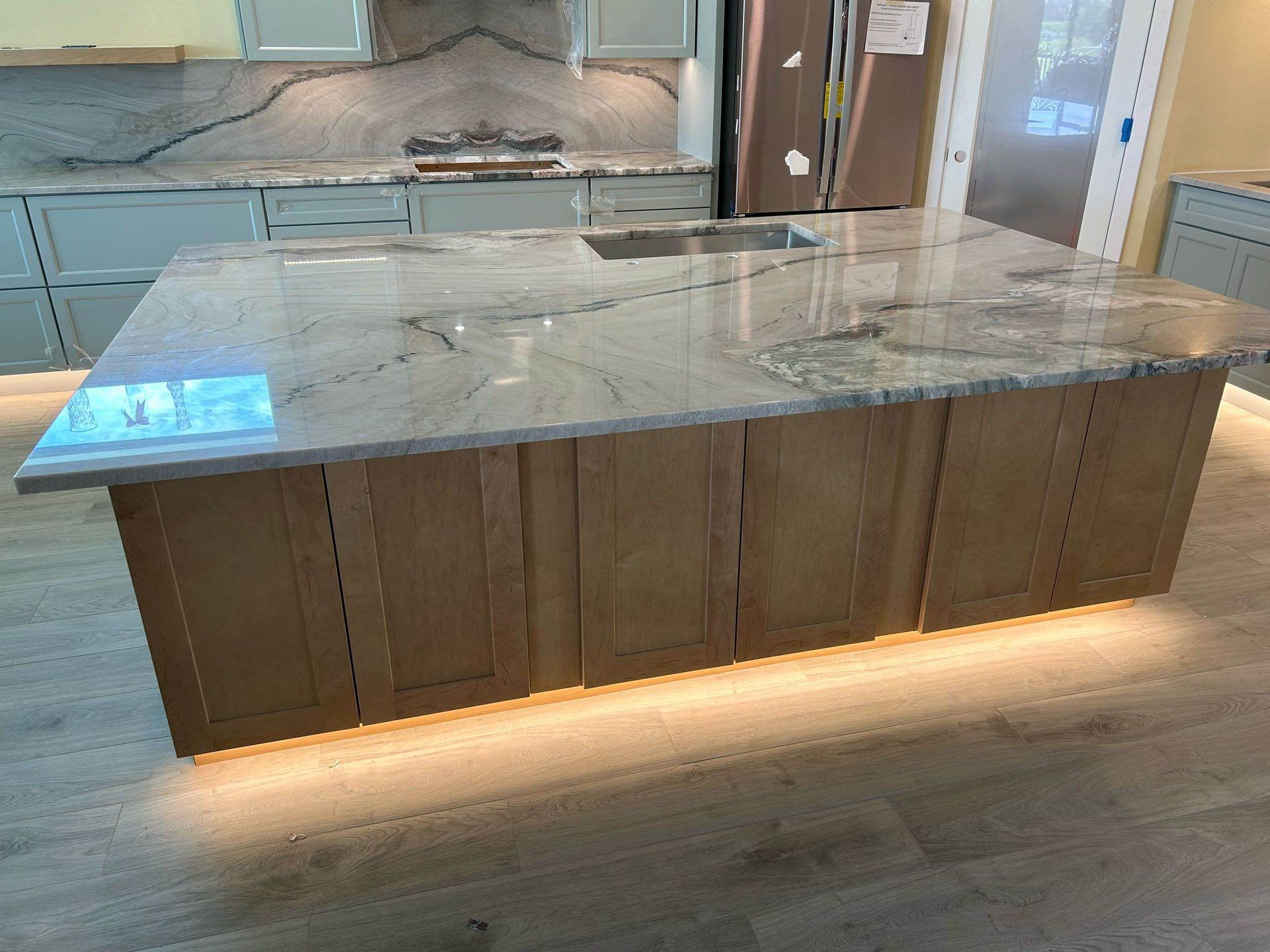 Kitchen island with a white marble countertop and warm under-cabinet lighting