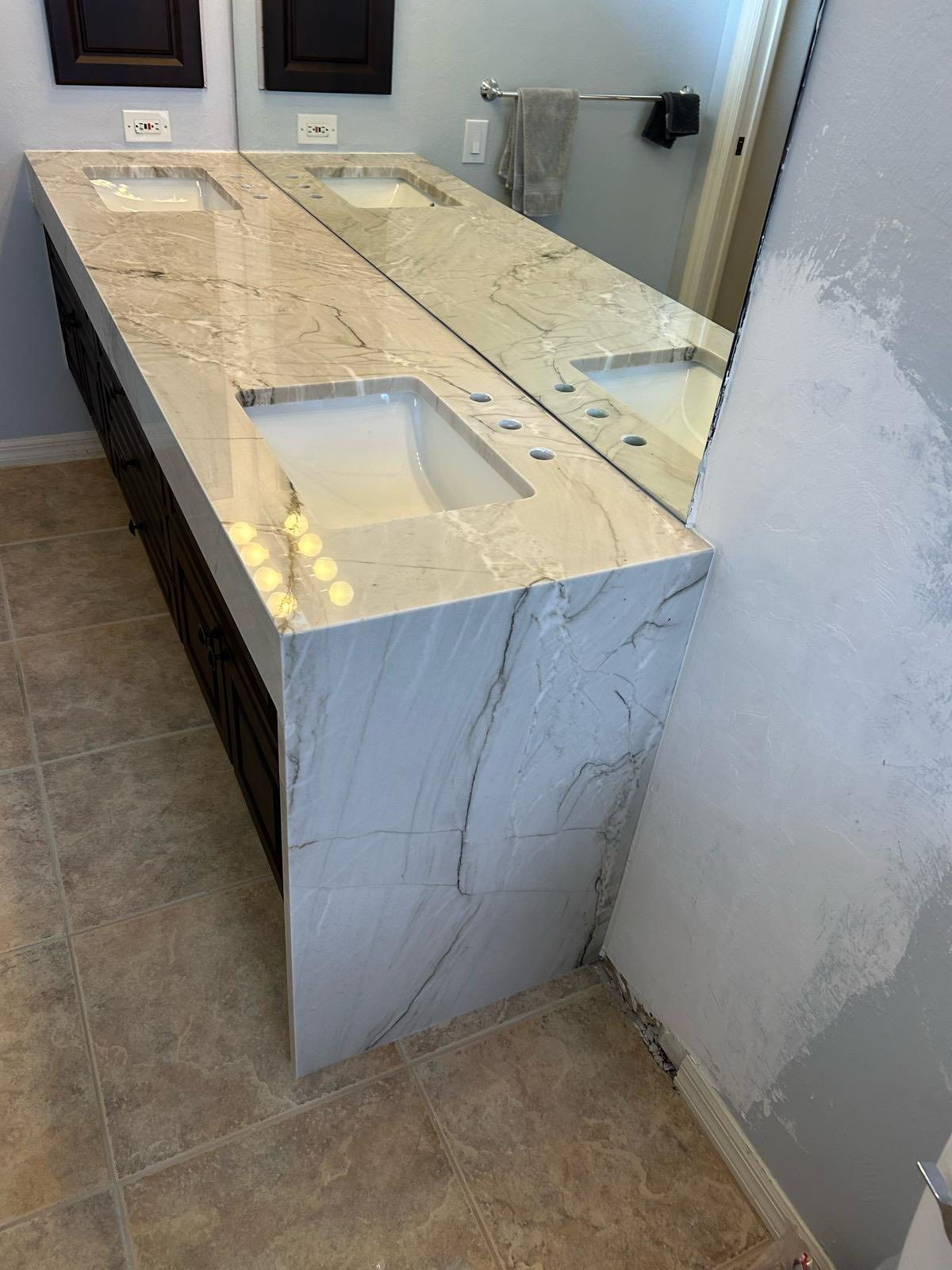 Double vanity with white marble countertops and rectangular sinks in a tiled bathroom