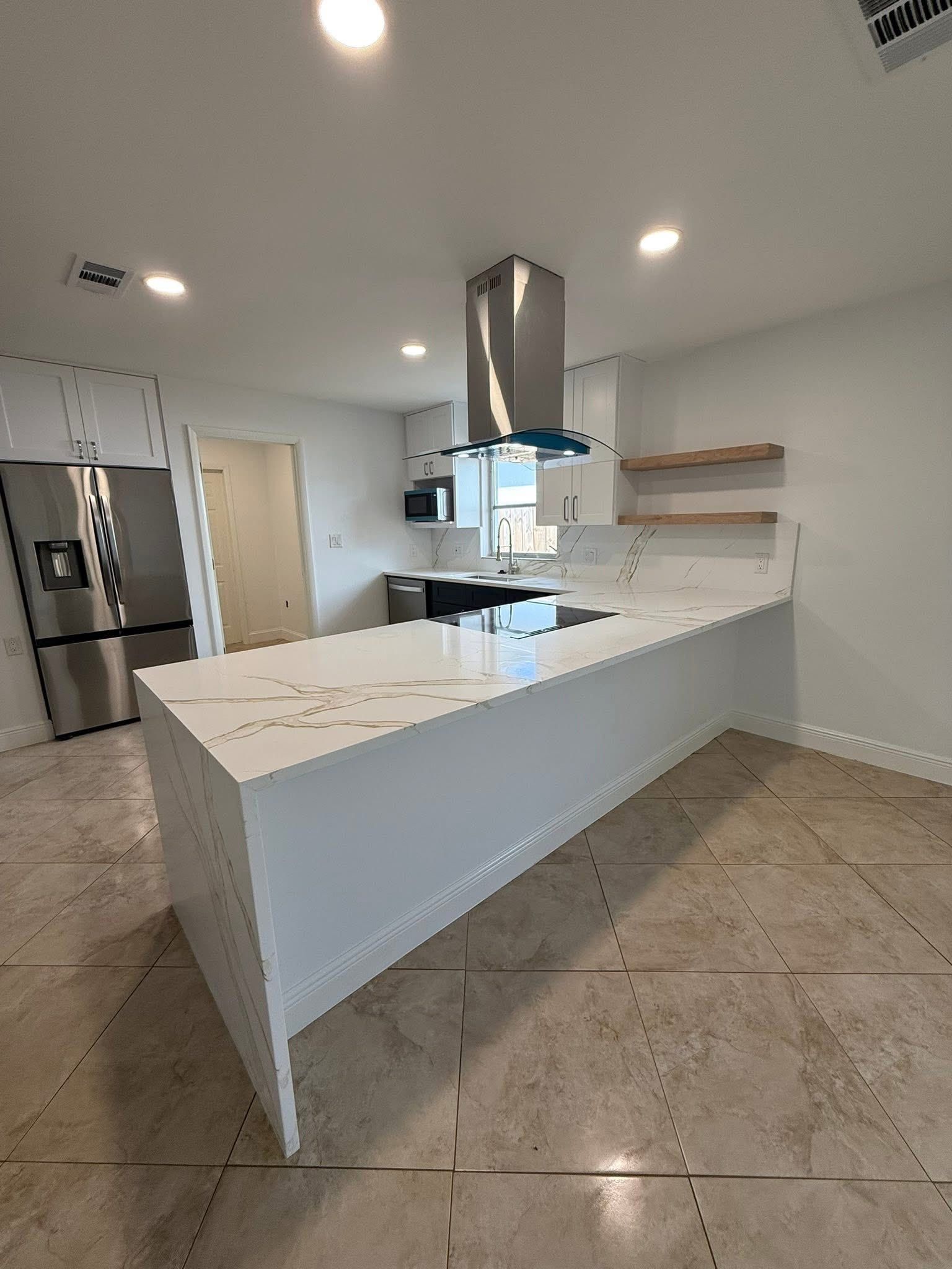 Bright modern kitchen with white island, stainless appliances, gray tile floor, and open shelves