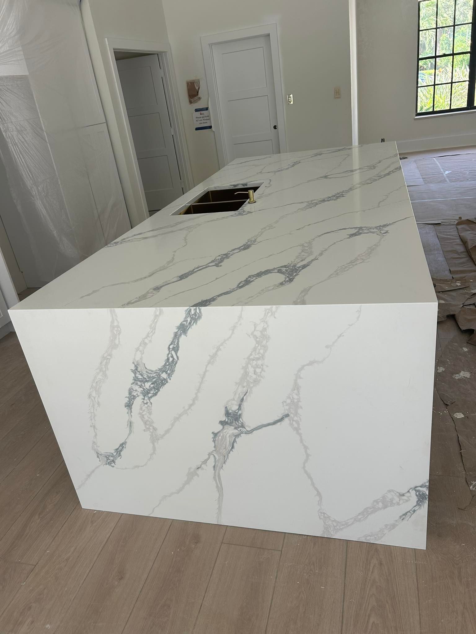 Modern kitchen island with white marble-look waterfall countertop in a bright room
