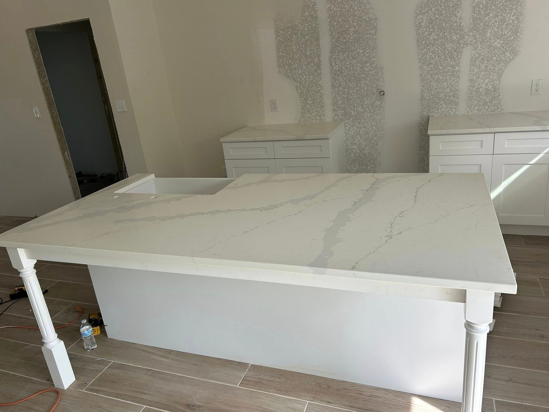 White marble dining table in a room with unfinished walls and two dressers nearby