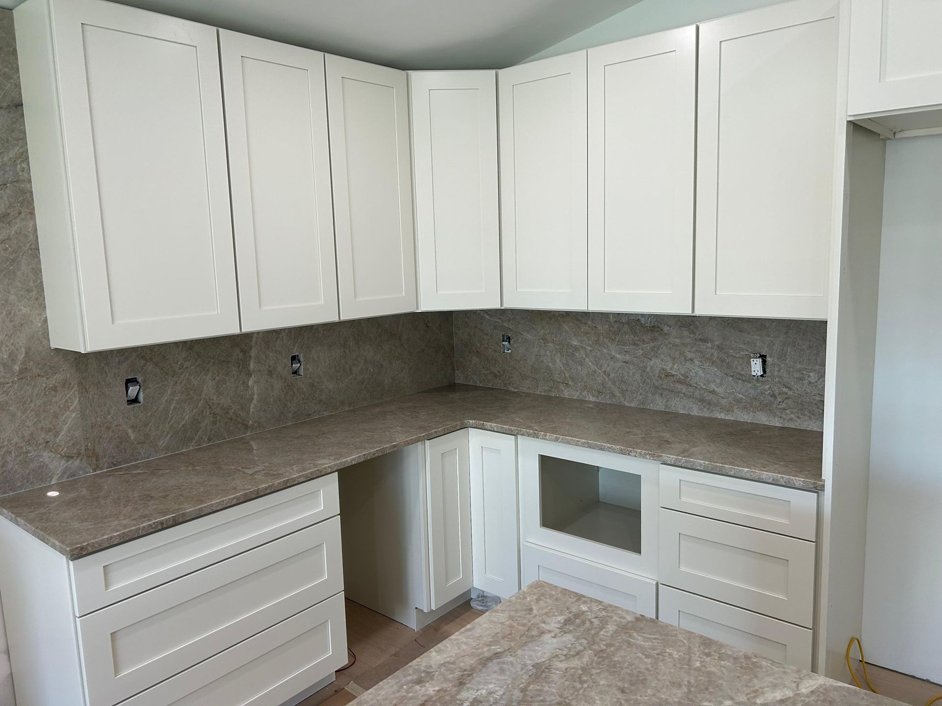 White kitchen with L-shaped granite countertops and built-in microwave under upper cabinets