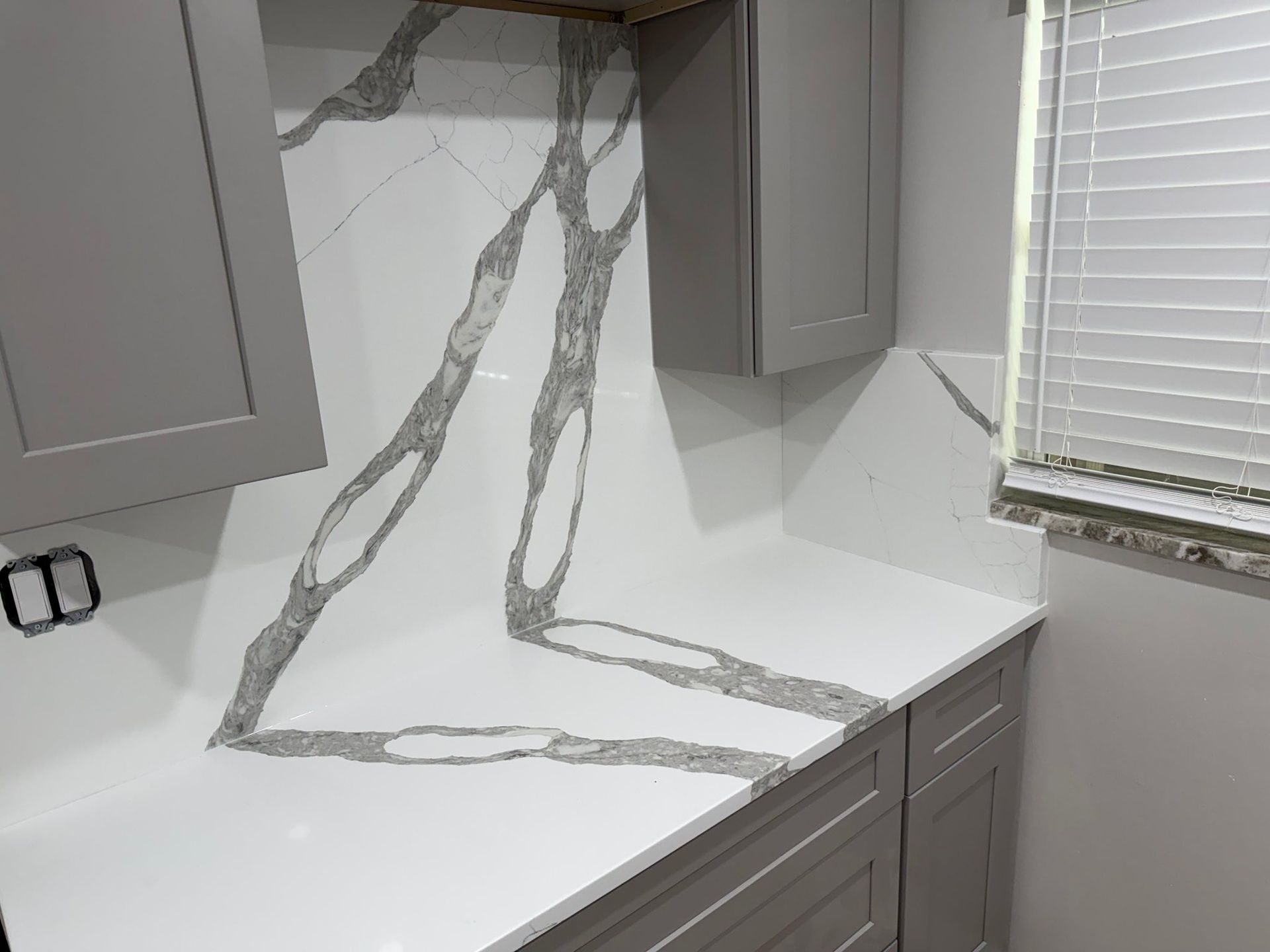 Modern kitchen countertop with gray and white marble veining and gray cabinets