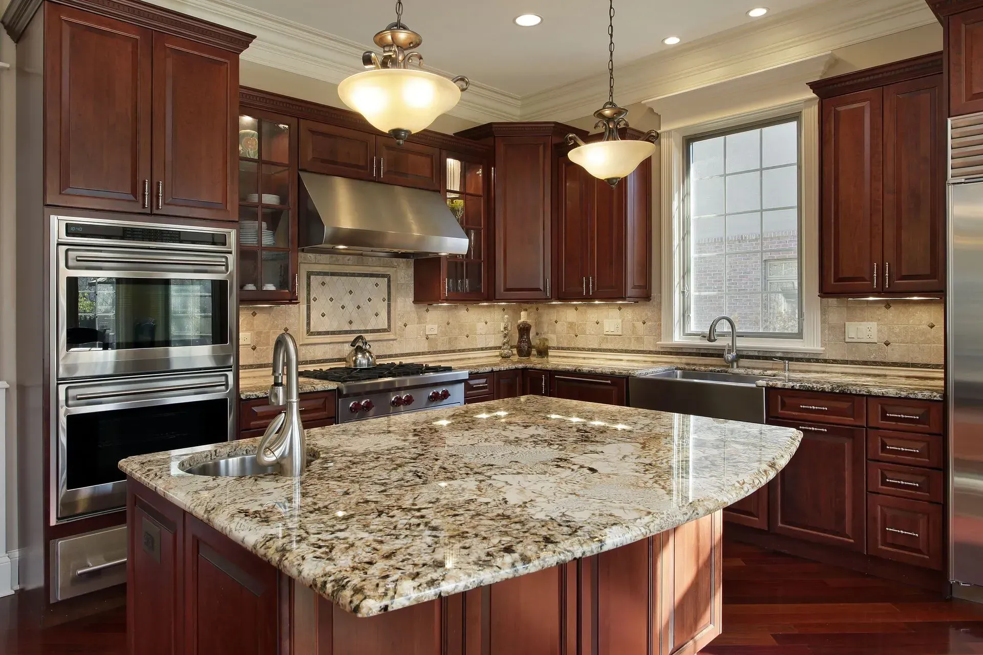 Luxury kitchen with dark wood cabinets, granite island, stainless appliances, and pendant lights