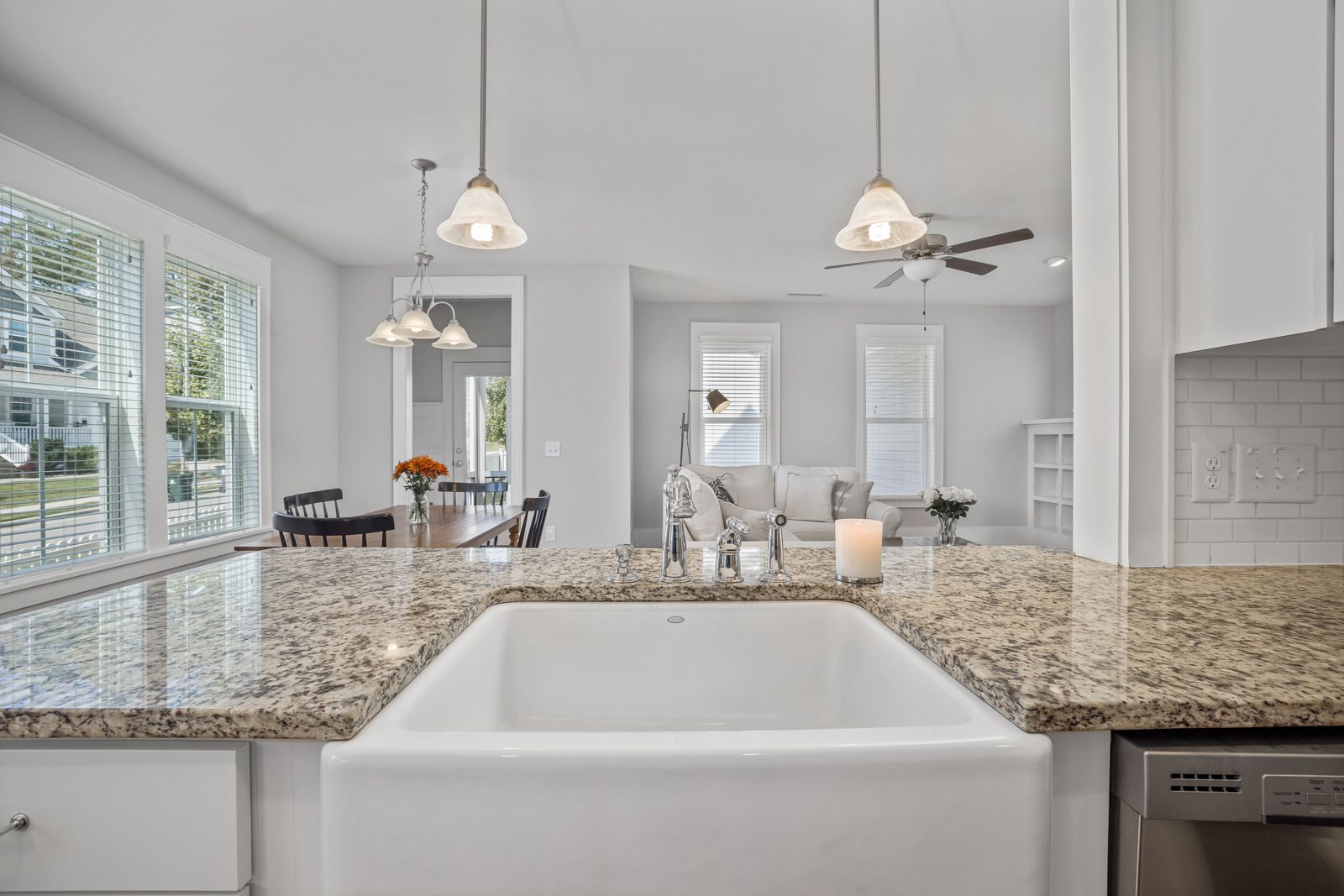Modern kitchen with white cabinets, marble waterfall island, stainless appliances, and large window.