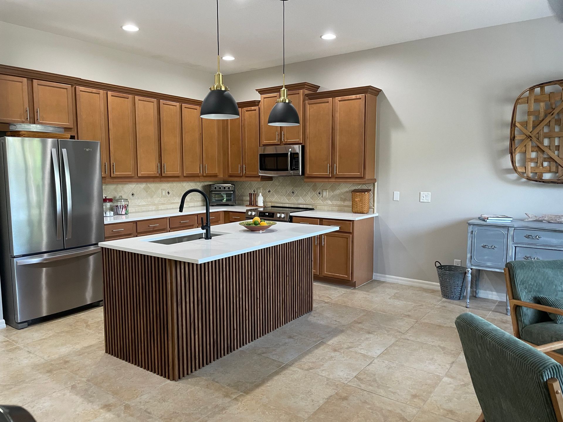 Modern kitchen with stainless fridge, wood cabinets, island, and pendant lights