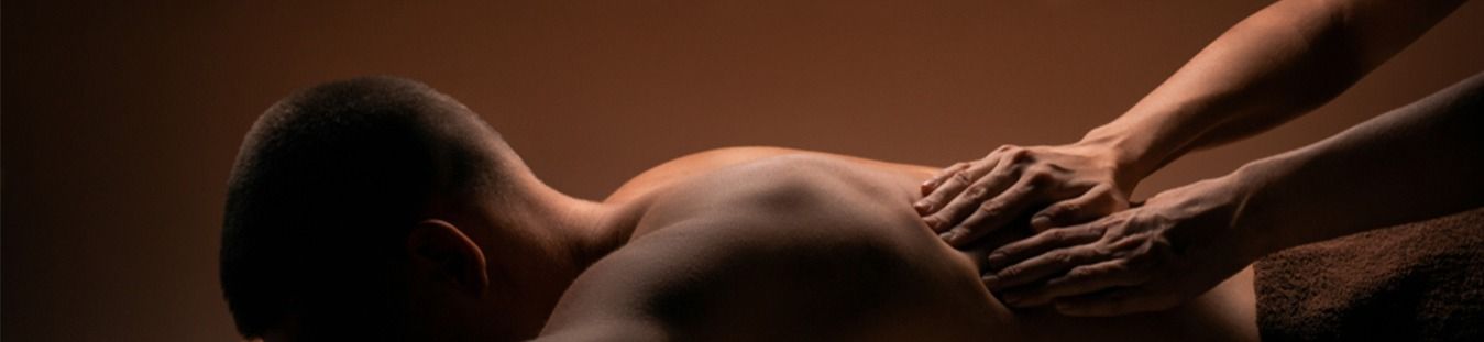 Person receiving a back massage, with two sets of hands kneading the person's back.