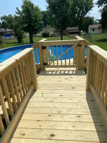 A wooden deck leading to a swimming pool.