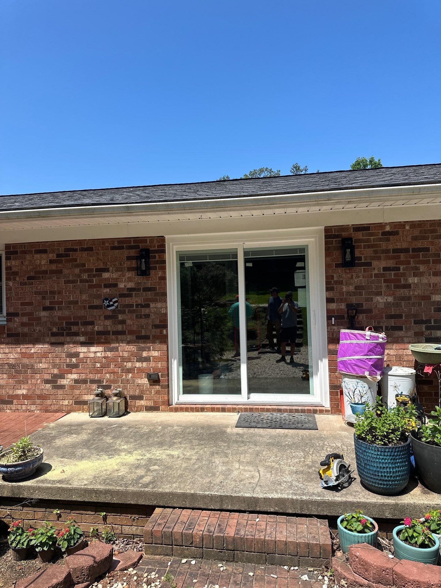 A brick house with a sliding glass door and potted plants in front of it.