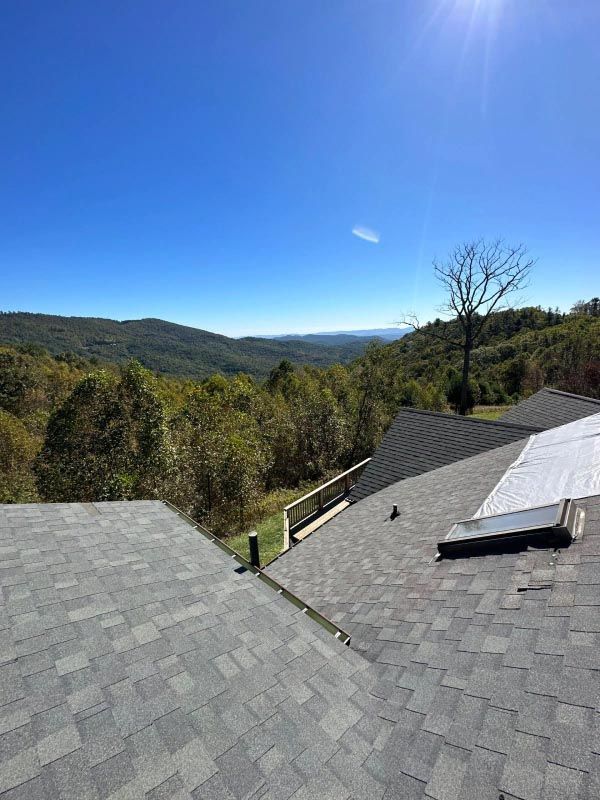The roof of a house with a view of the mountains and trees.
