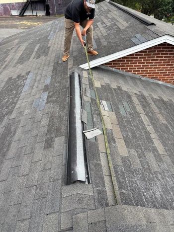 A man is measuring a roof with a tape measure.
