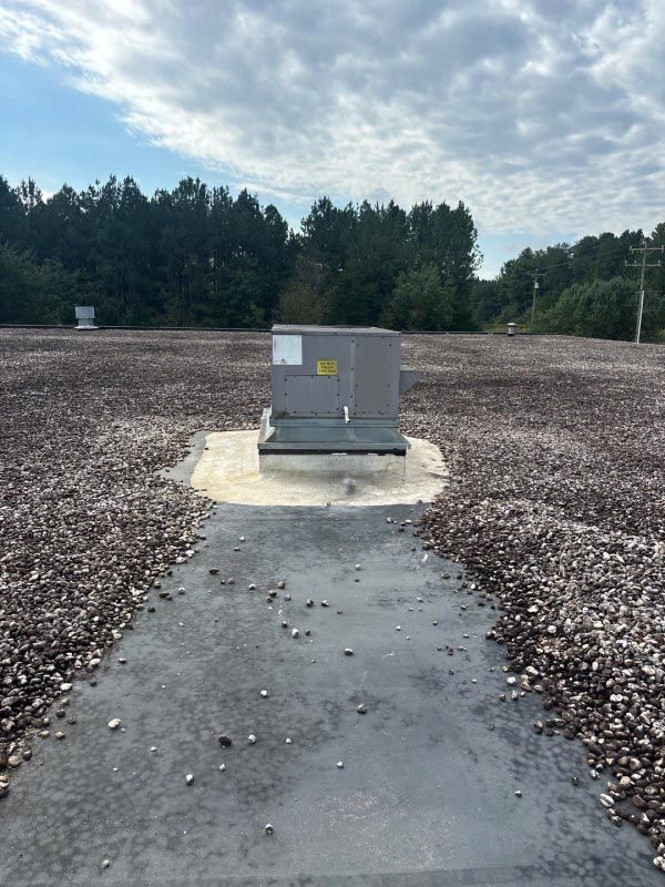 A gray box is sitting in the middle of a gravel field.