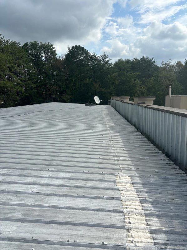 A roof with a satellite dish on it and trees in the background