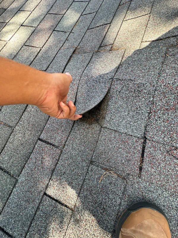 A person is holding a piece of shingles on a roof.