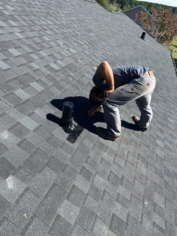 A man is bending over on top of a roof.