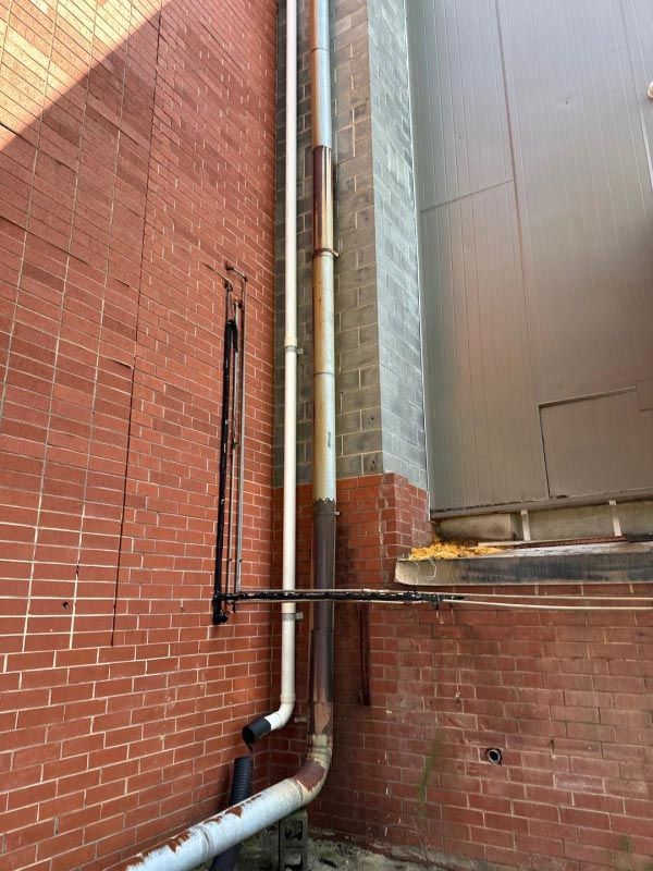 A brick wall with a drain pipe attached to it.