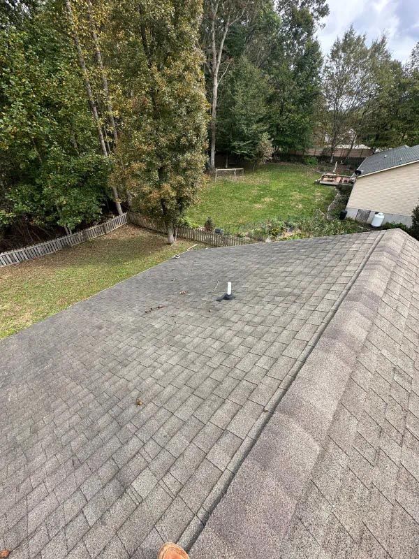 A roof with a chimney on it and trees in the background.