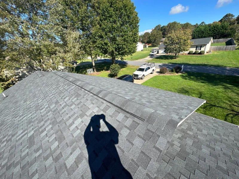 A person is taking a picture of the roof of a house.