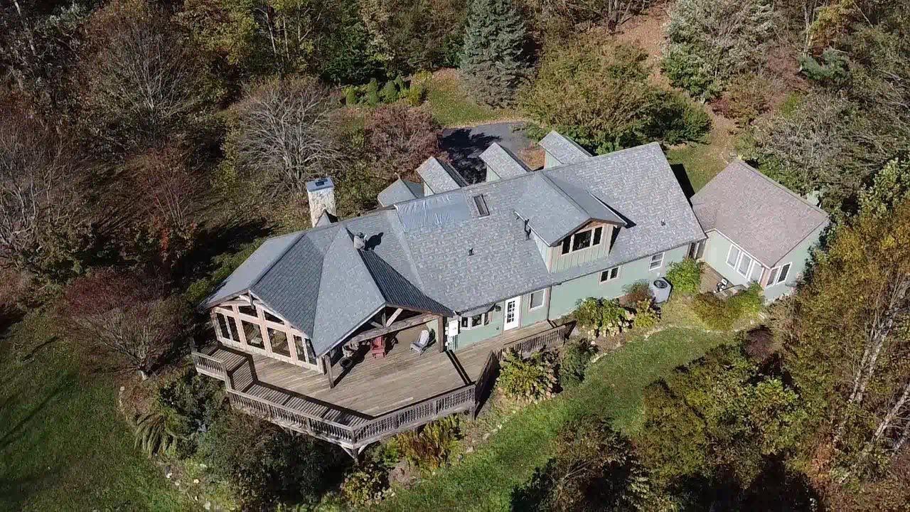 An aerial view of a large house on top of a hill surrounded by trees.