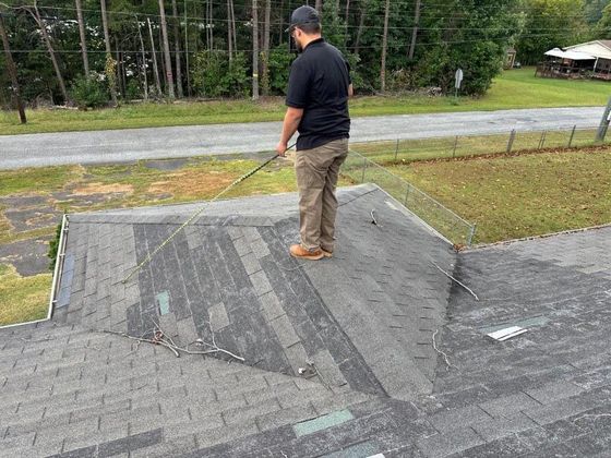 A man is standing on top of a roof with a hose.