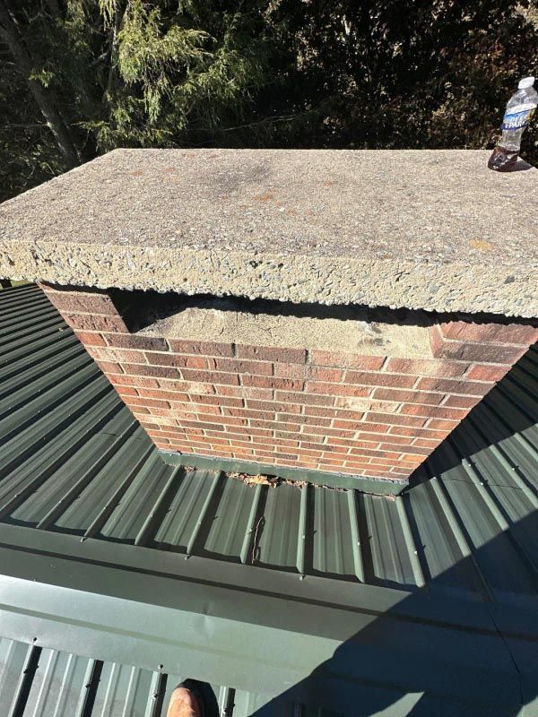 A brick chimney is sitting on top of a metal roof.