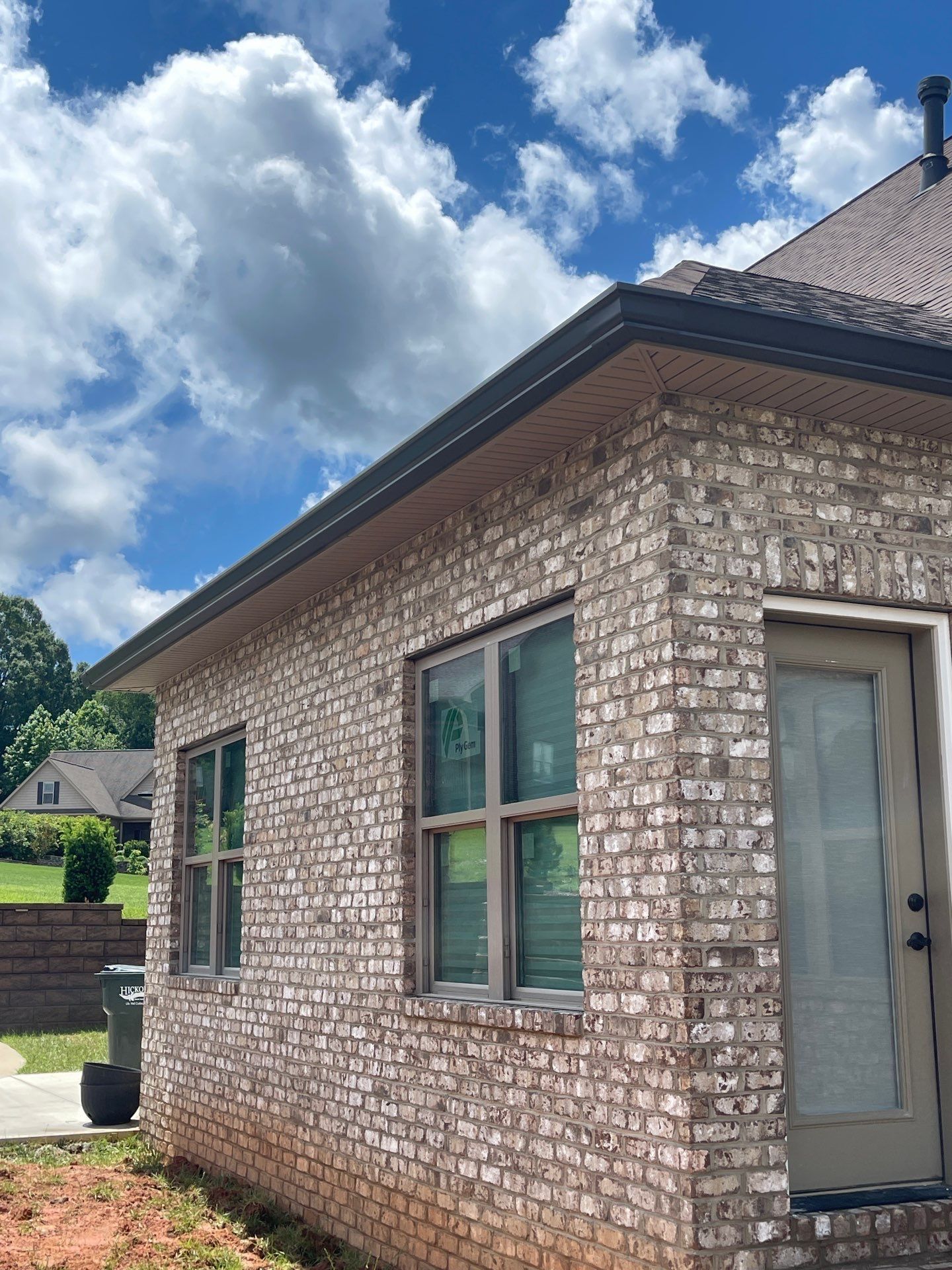 A brick house with a door and windows on a sunny day.