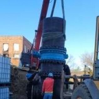 A large pipe is being lifted by a crane.