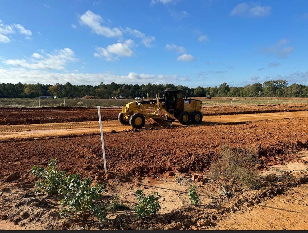 A yellow tractor is moving dirt on a dirt road.